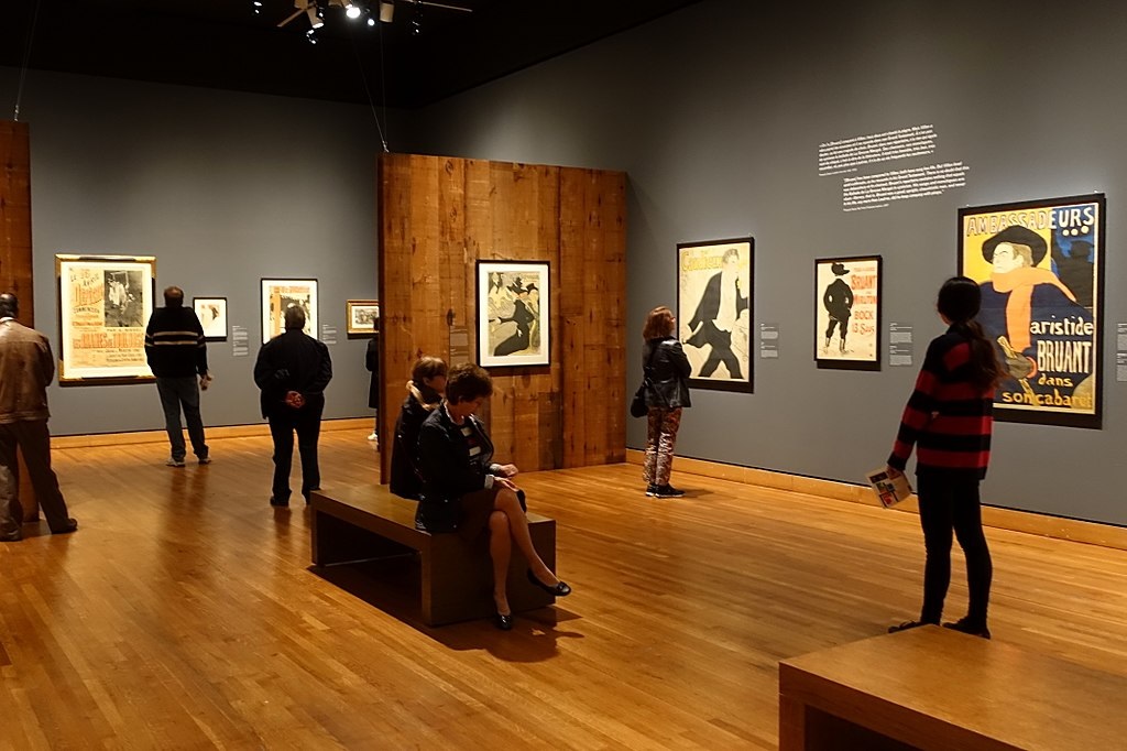 An Exhibit room in the Montreal Museum of Fine Arts showing viewers looking at iconic poster art