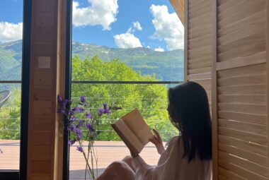 Woman reading one of our best travel books with mountains in the background