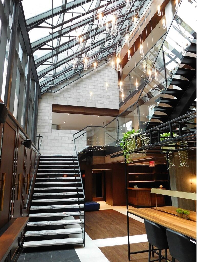 Beautifully designed modern lobby of Hotel William Gray which is located in Old Montreal showing open staircase, clear railings, hanging plants and desk area
