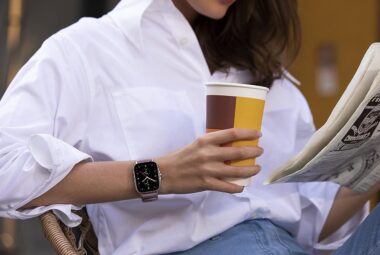 Woman wearing a Smartwatch holding a coffee and newspaper