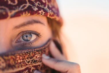 Western woman covering face except showing one of her pretty blue eyes